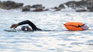 A woman swimming in open water with a tow float