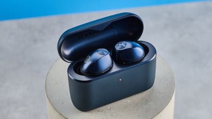 the sennheiser momentum 5 true wireless earbuds in navy photographed with the blue tom's guide background