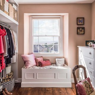 wardrobe with pink wall white seat and wooden flooring