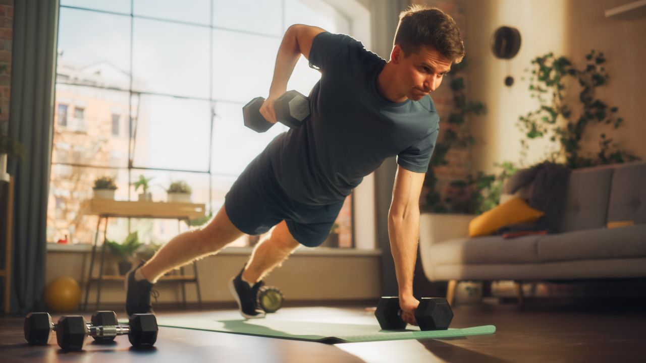 A man performing a renegade row with a pair of dumbbells 