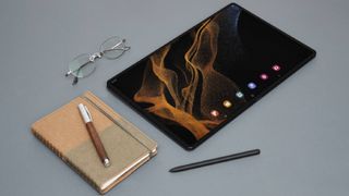 Galaxy Tab S8 Ultra on a table nest to s Pen, glasses and notebook