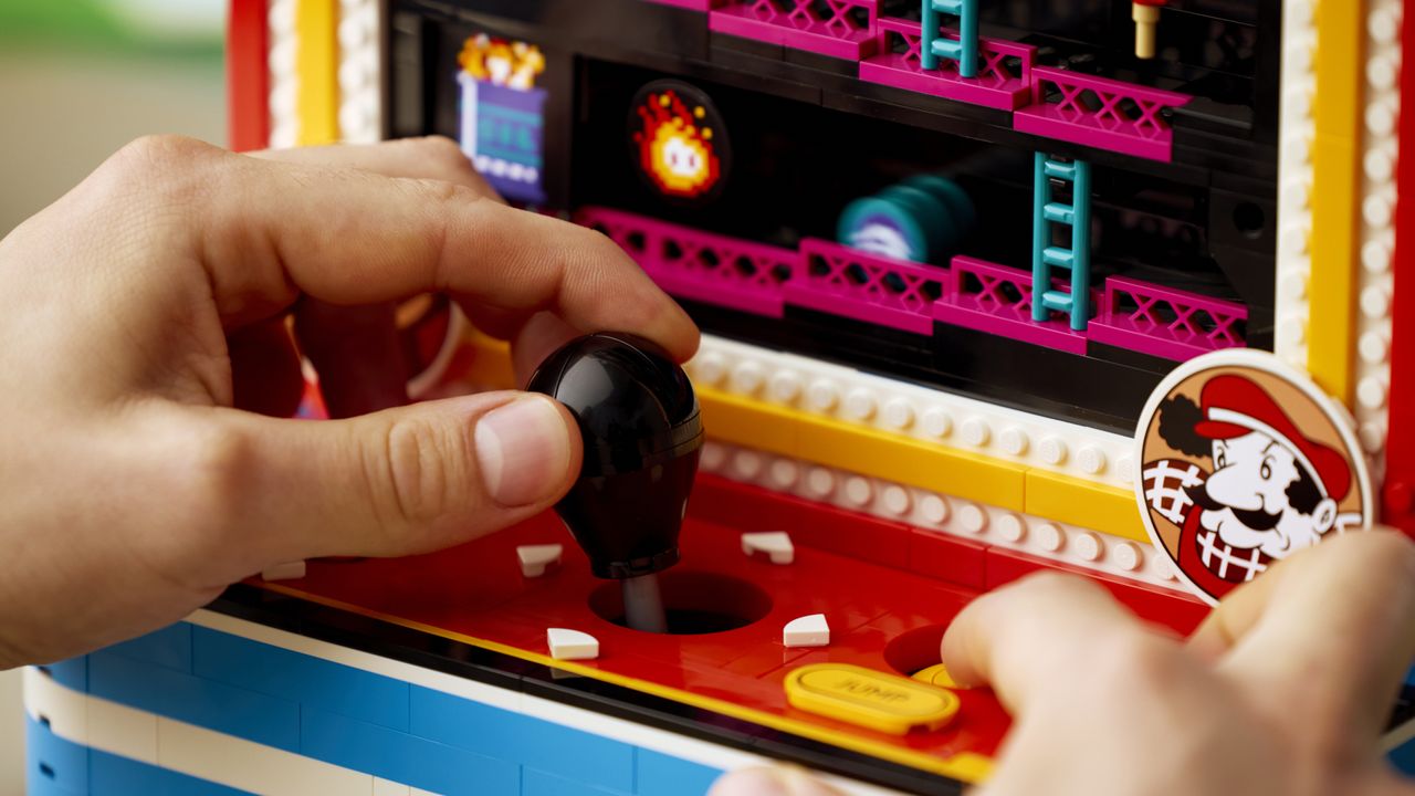 A hand moves the joystick and presses buttons for the Lego Donkey Kong Arcade set