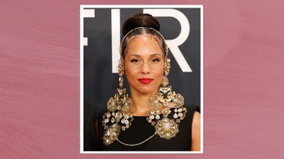 Image of Alicia Keys with brunette hair braided into a bun, wearing minimal makeup and bright red lipstick, on a deep mauve background