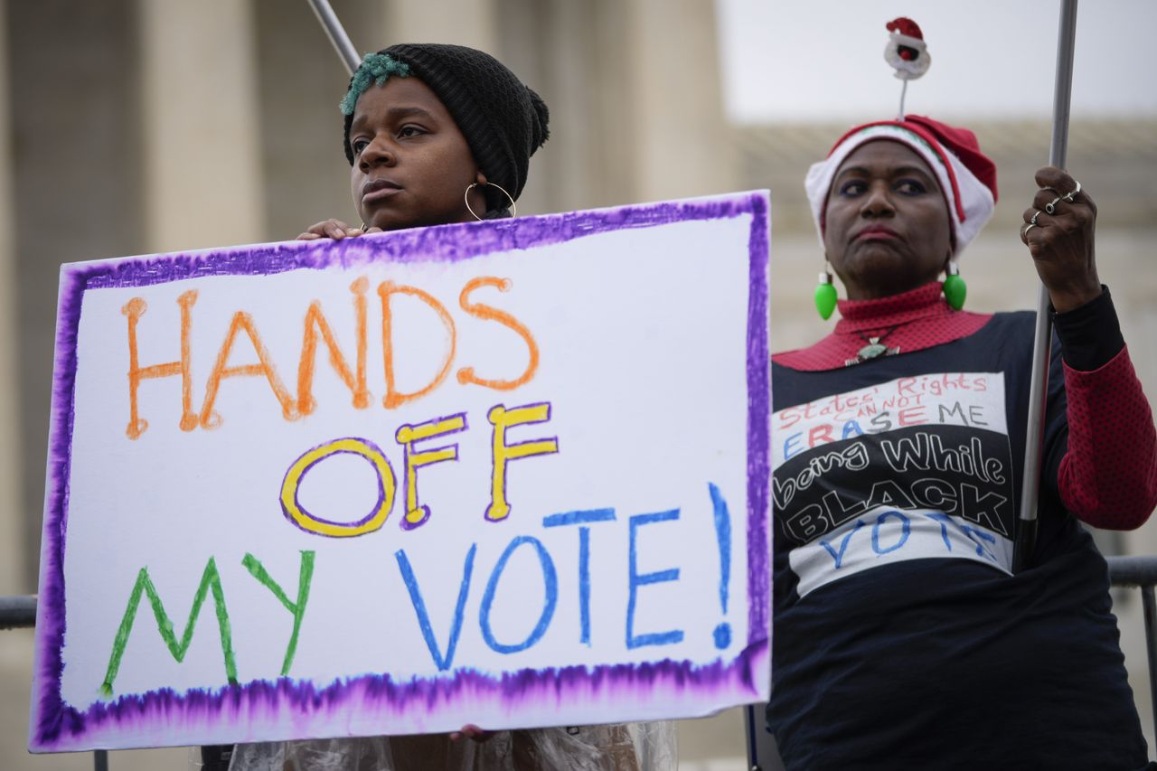 A photograph of voting rights activists outside the U.S. Supreme Court holding a sign saying &amp;quot;Hands Off My Vote!&amp;quot;