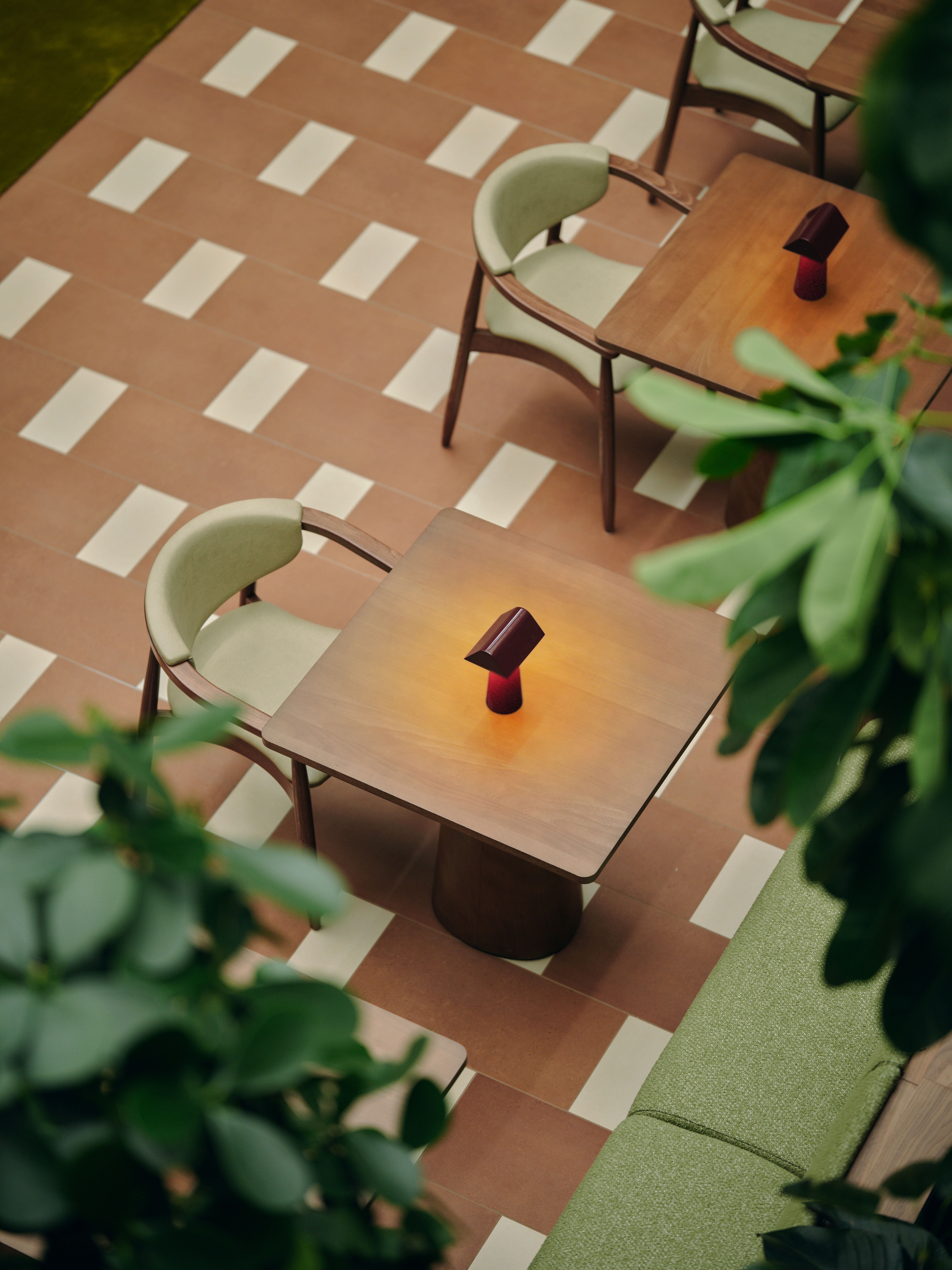 A series of interior shots of a workspace designed with terracotta-hued checkered floors, coffered ceilings in wood and back-lit blocks, pendant, see-through lighting, mid-century furniture, 
