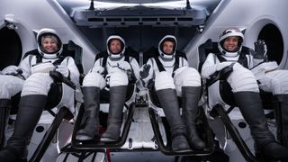 The four astronauts of SpaceX&#039;s Polaris Dawn private mission pose in black and white spacesuits inside their Dragon capsule.