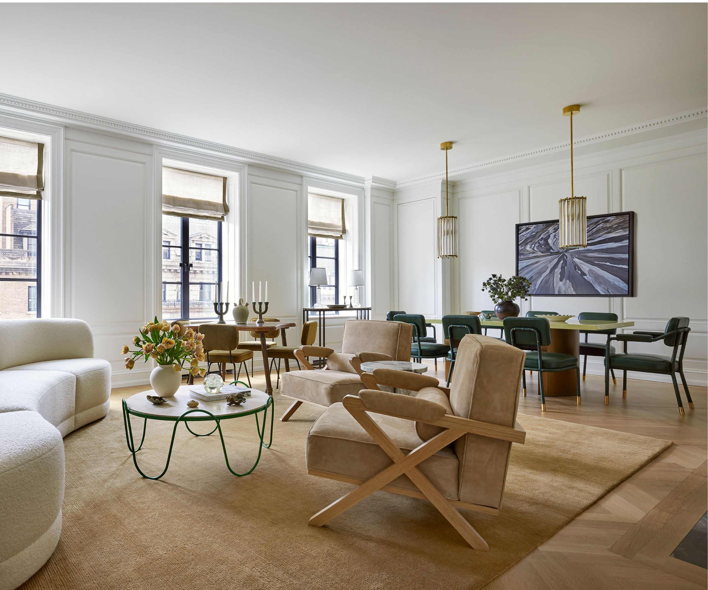 an open concept living room with a white couch, beige armchairs, and a dining table in the background.