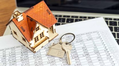 little house and keys on top of financial papers