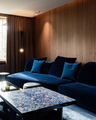 navy blue sofa in a home cinema with walnut paneling