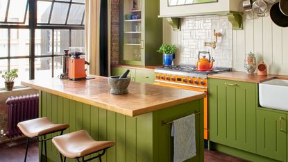 a colorful kitchen design with green cabinets and an orange range