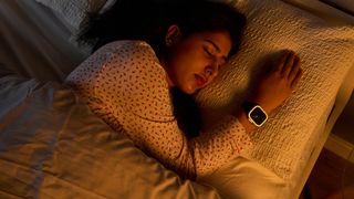 A close up of a woman lying in bed wearing an Apple Watch