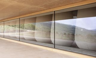 The glazed facade reflects the vineyards and nature beyond at Les Davids winery