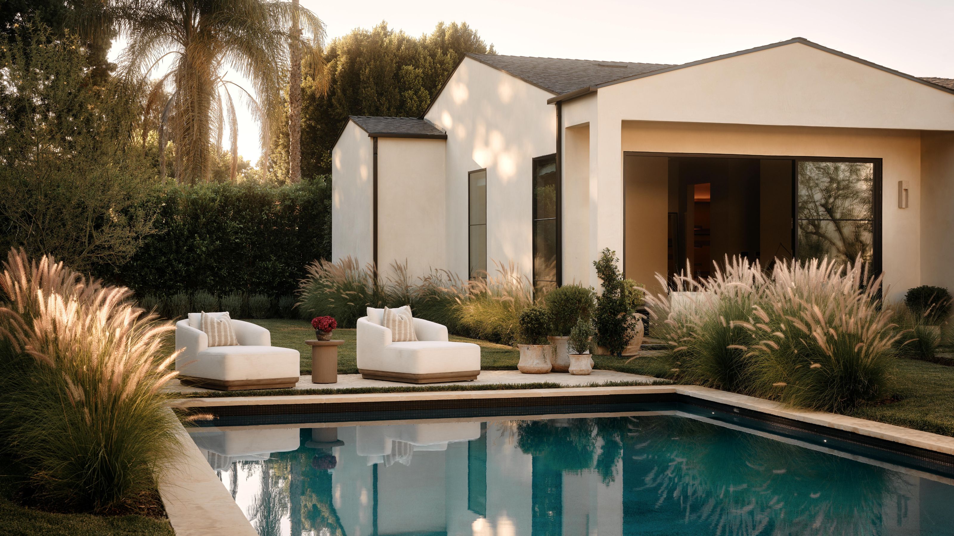 a large organic modern home exterior with palm trees and a pool