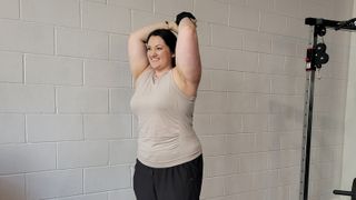 Personal trainer Rebecca Stewart performs overhead tricep extension with heavy dumbbell