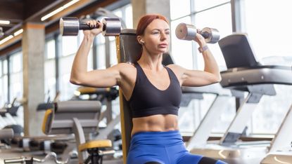 Woman performs a seated dumbbell press