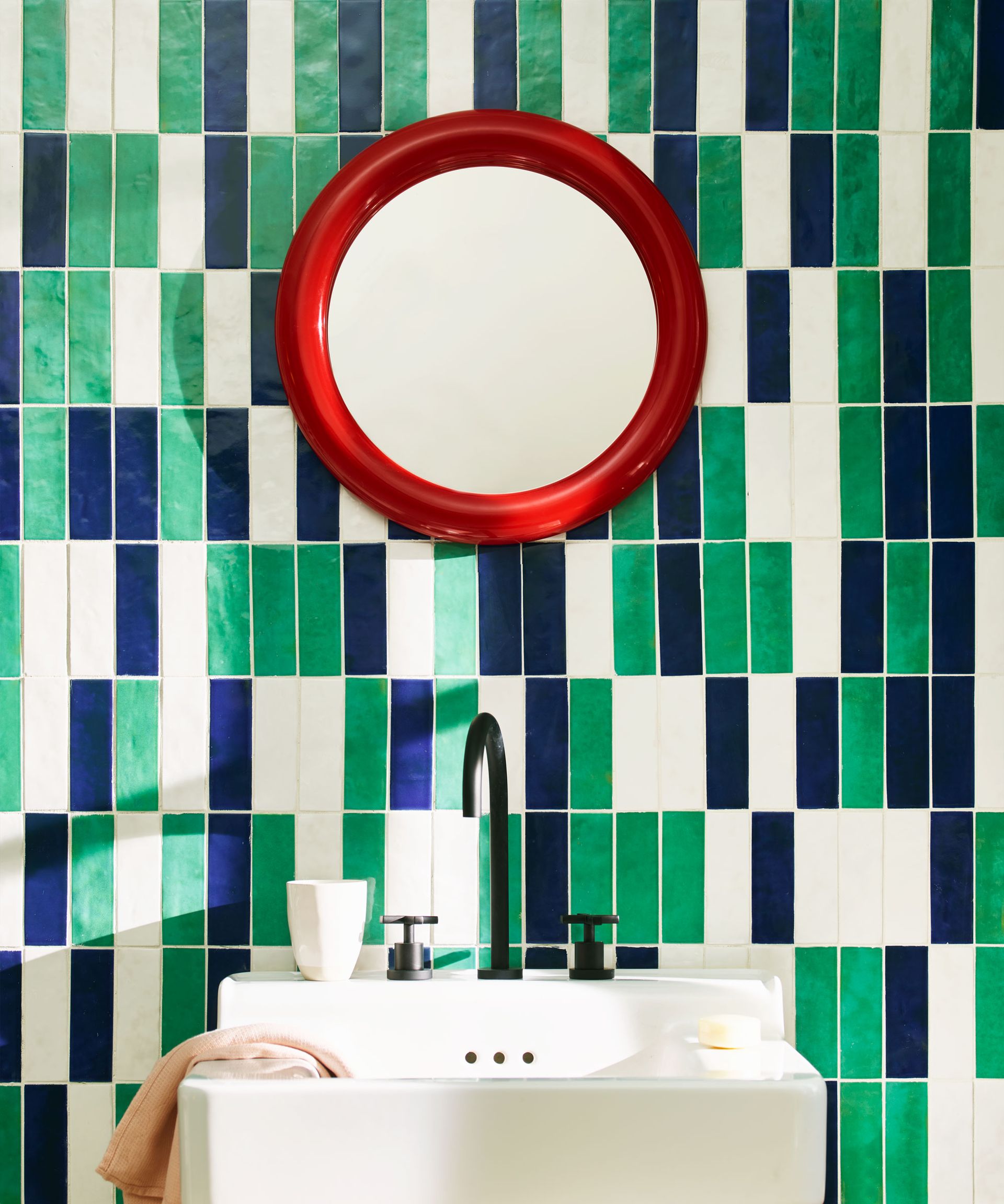 bathroom basin with graphic tile design and colourful red round mirror