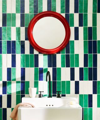 bathroom basin with graphic tile design and colourful red round mirror