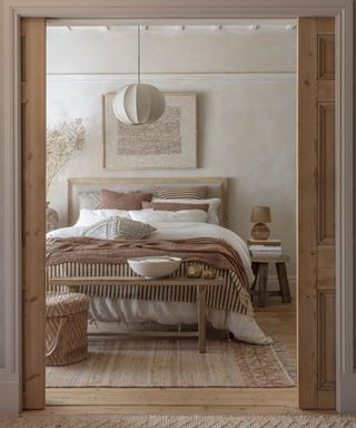 Wooden door, bench, off white walls, bed