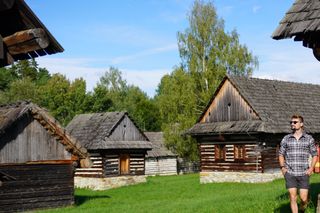 Image shows Stefan walking around the traditional log houses in the Museum of the Slovak Village