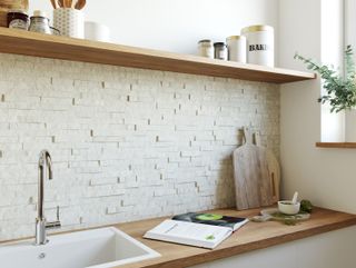 white neutral split mosaic tile backsplash in a white kitchen with wood countertops and natural wood cooking utensils