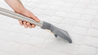 Vacuum cleaning the surface of a white mattress