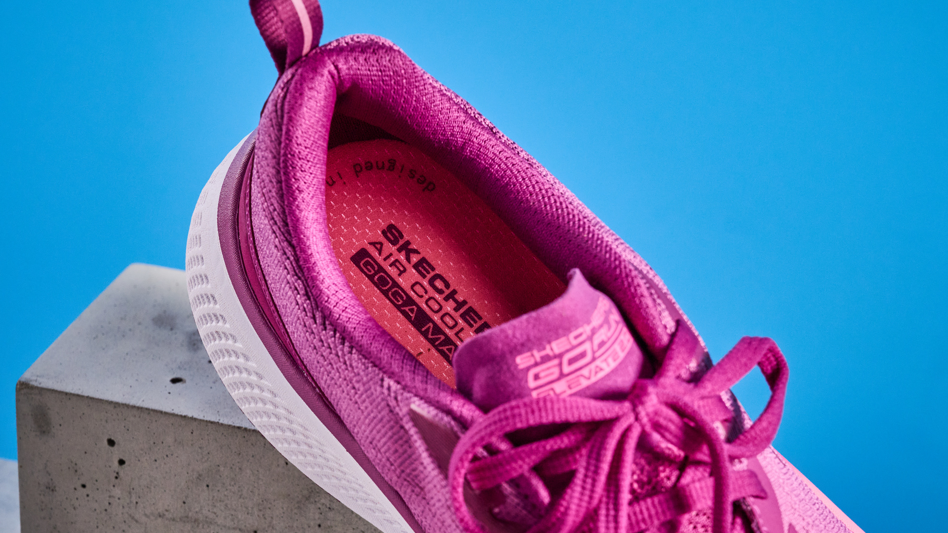 the skechers go run elevate 2.0 running shoes in the women's style, in fuchsia pink, photographed against a blue background