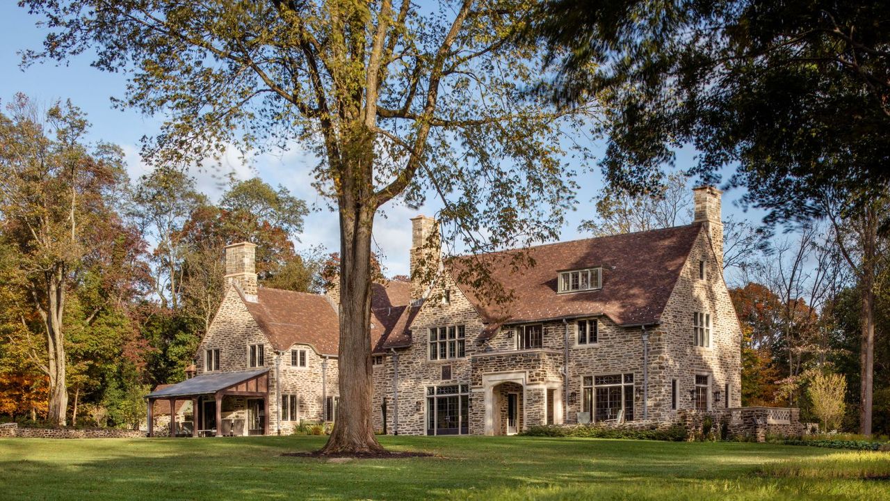 exterior of stone built country home with blue skies and mature trees