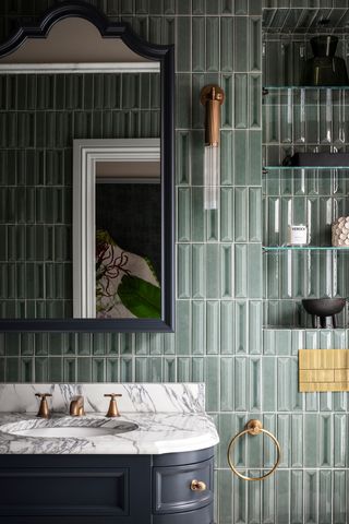 A bathroom with dark green wall tiles and chrome fixtures