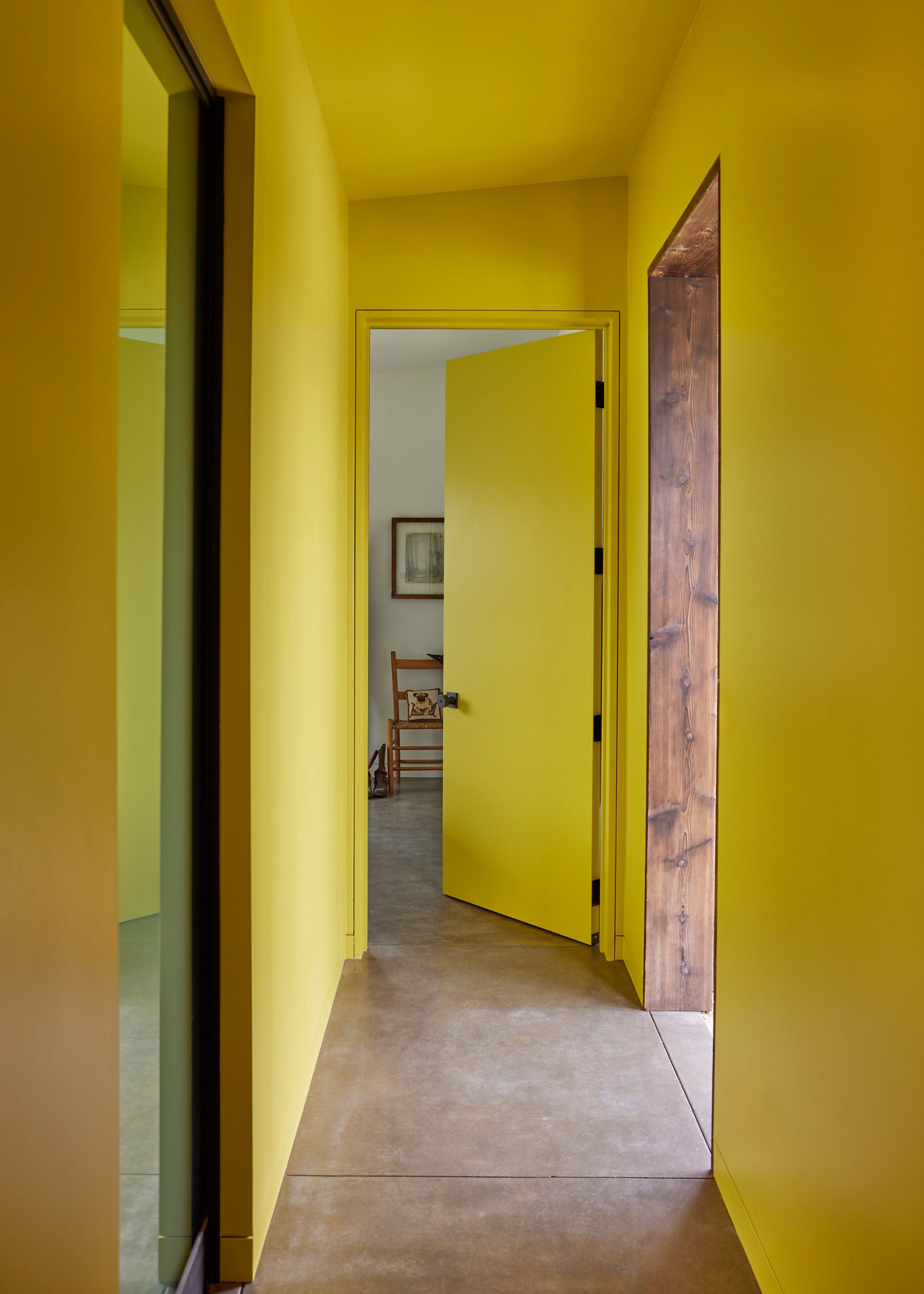 A modern minimalist hallway color-drenched bright yellow and concrete flooring.