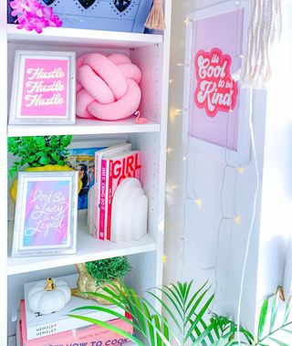 A colorful bookshelf with fairy lights and wall art next to it