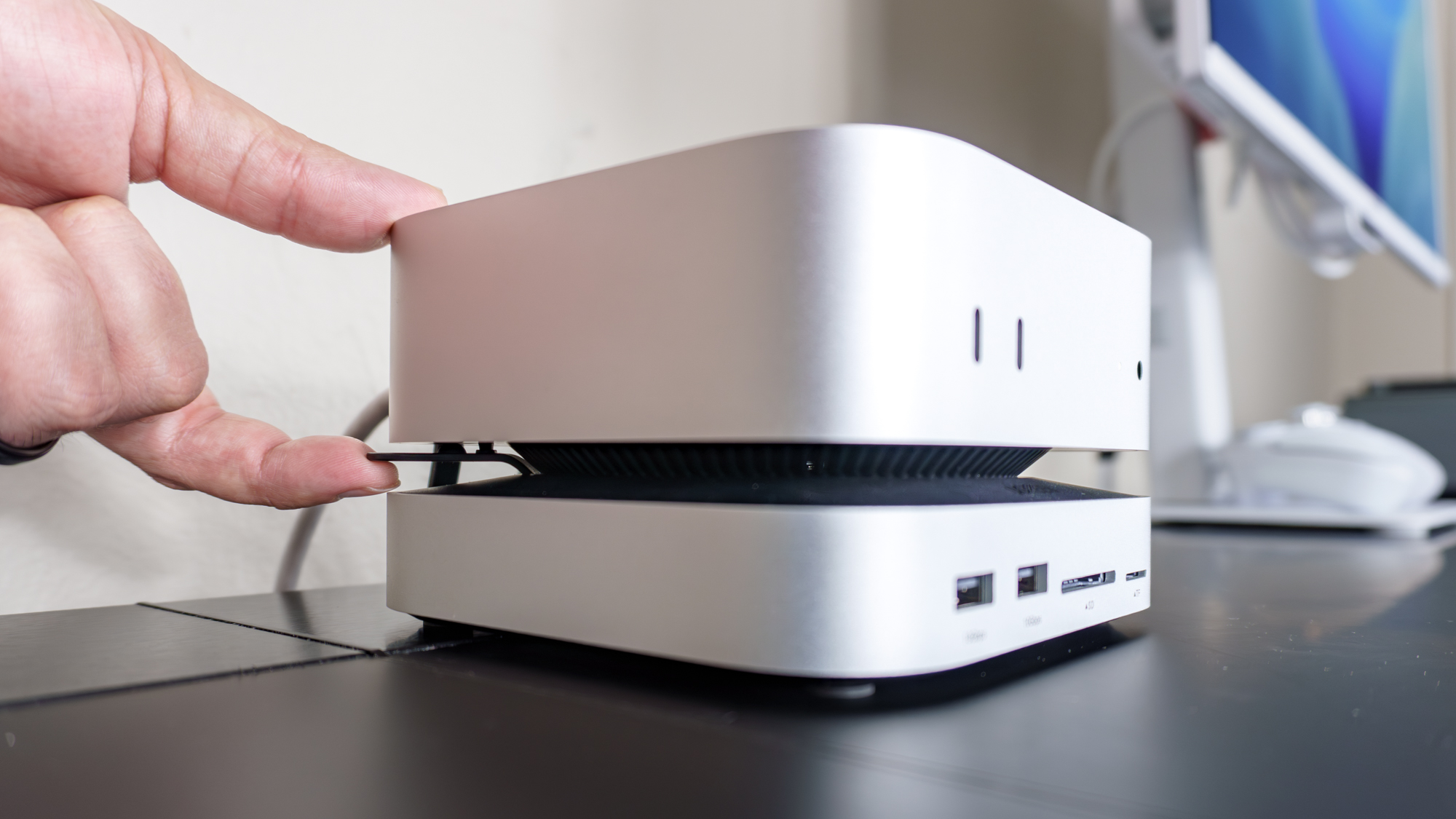 A person using the Ugreen Mac Mini M4 Dock &amp;amp; Stand to more easily reach the Mac mini M4's power button