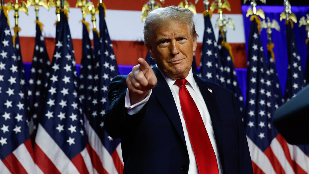 President-elect Donald Trump stands in front of American flags, pointing to the crowd at Florida campaign event