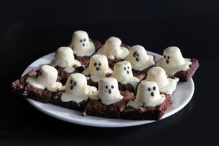 A plate of brownies with melted ghost marshmallows on top.