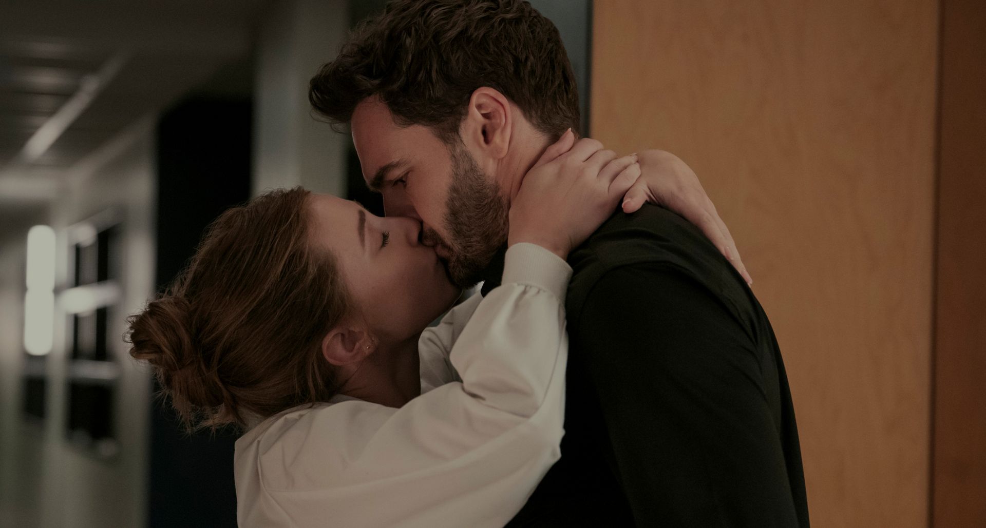 lili reinhart as olive and tom bateman as adam kissing in a hall in the movie the love hypothesis