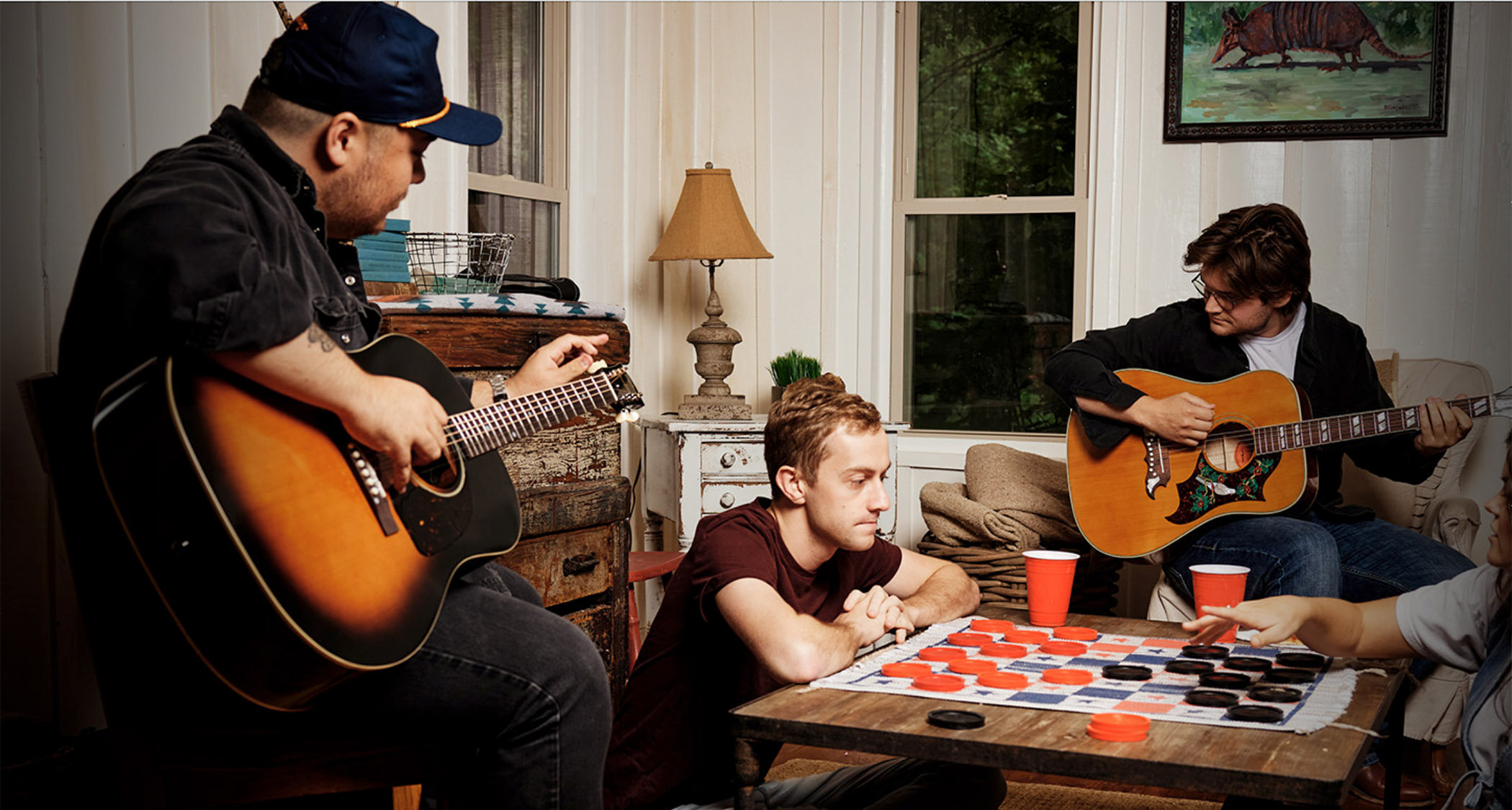 Epiphone Inspired By Gibson Custom 2025: two people play a board game whole two others jam on Dove and J-45 acoustic guitars
