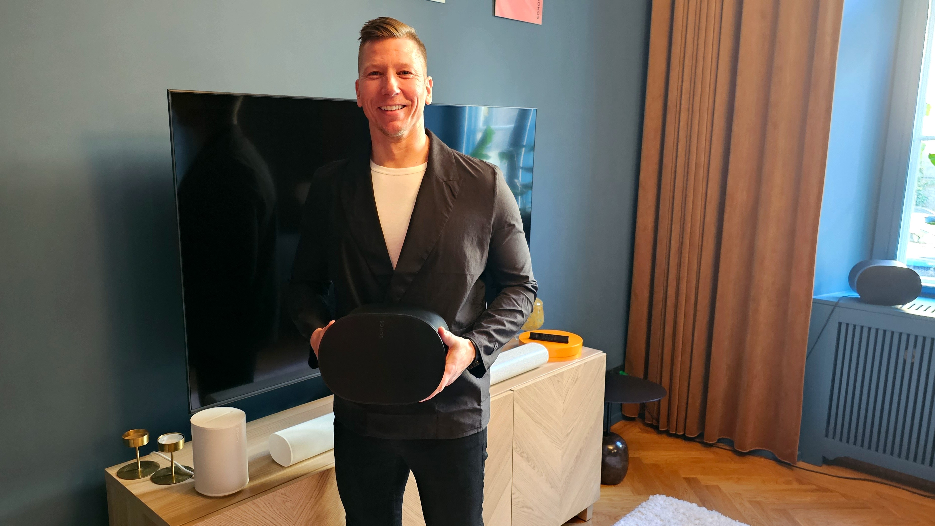 Aki Laine står i en stue og holder Sonos Era 300 i hænderne