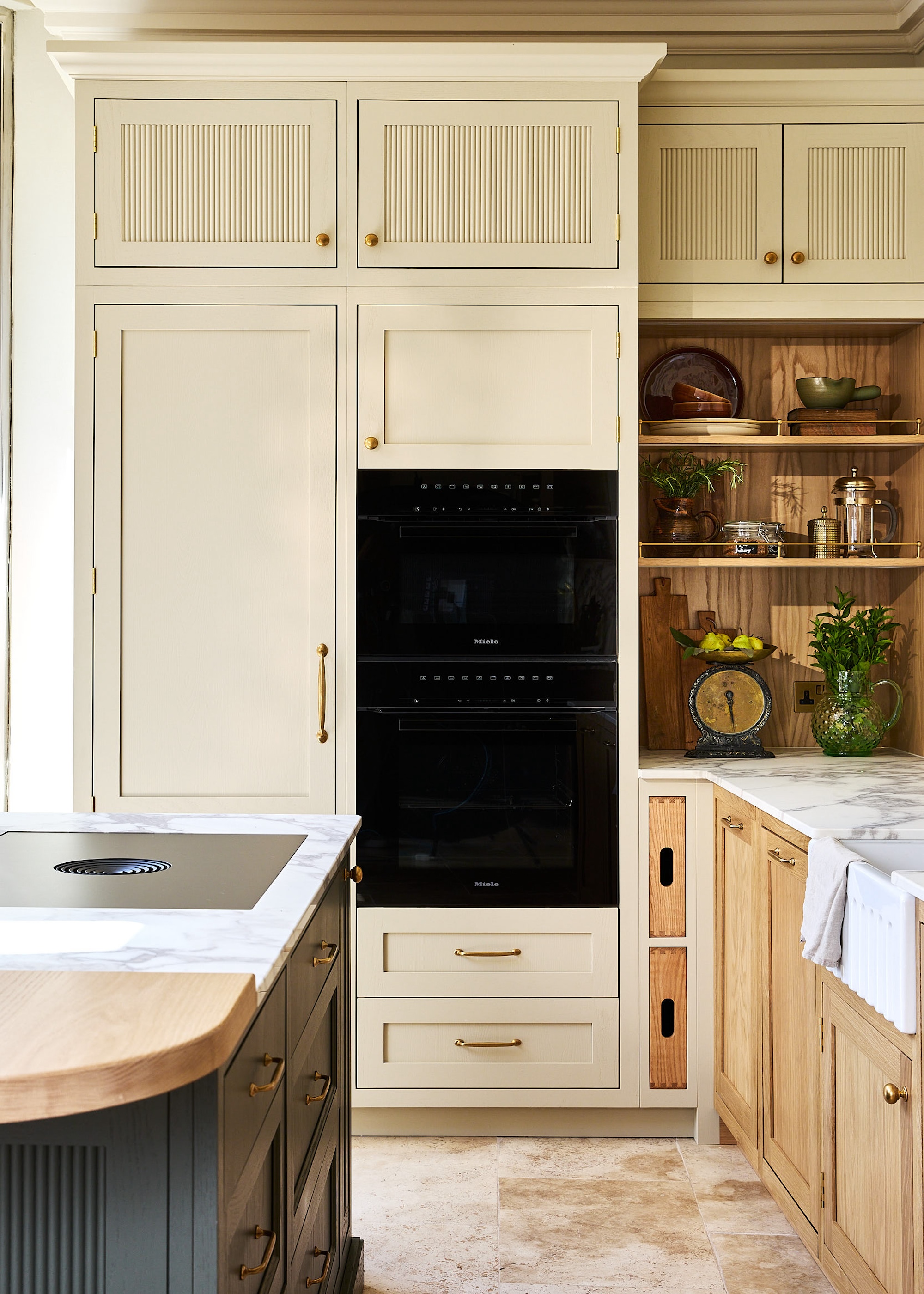 A cream Shaker style kitchen paired with oak based units, open shelving and a kitchen island in dark blue