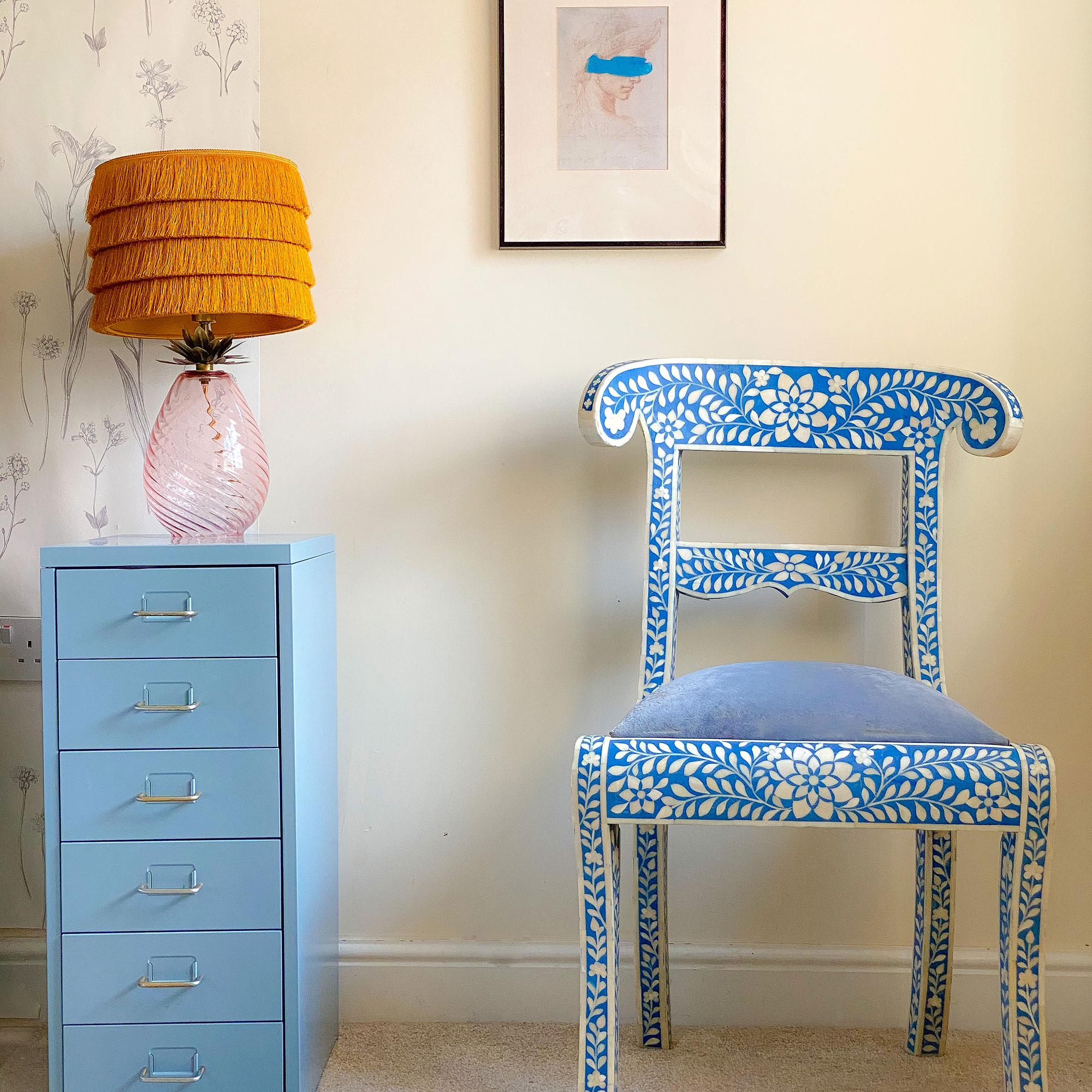 chair painted with white and blue florals beside pale blue filing cabinet