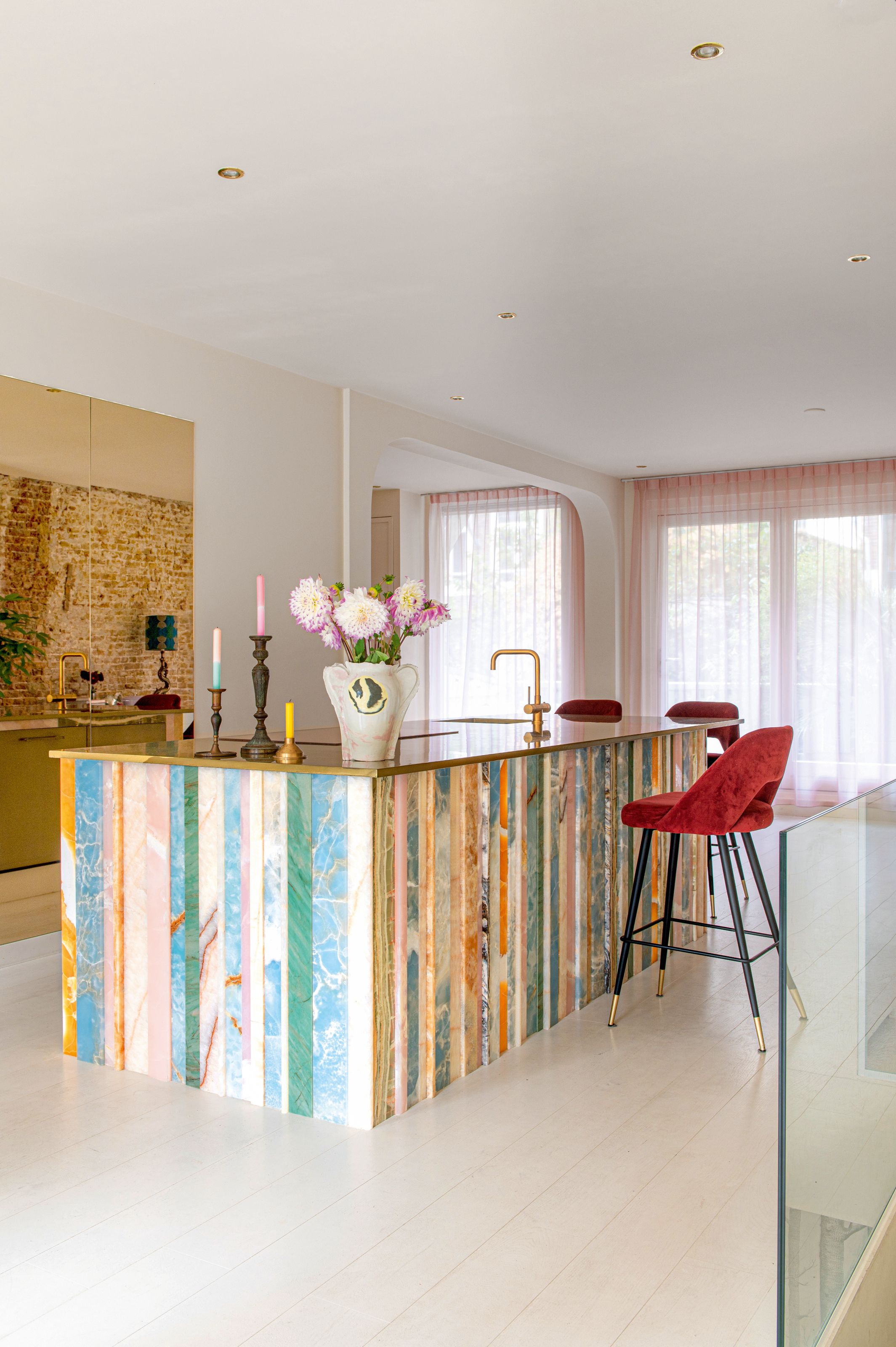 Kitchen with island clad in multicolor strips of onyx
