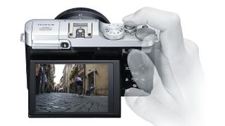 Silhouette of a hand holding the Fujifilm X-M1 against a white background