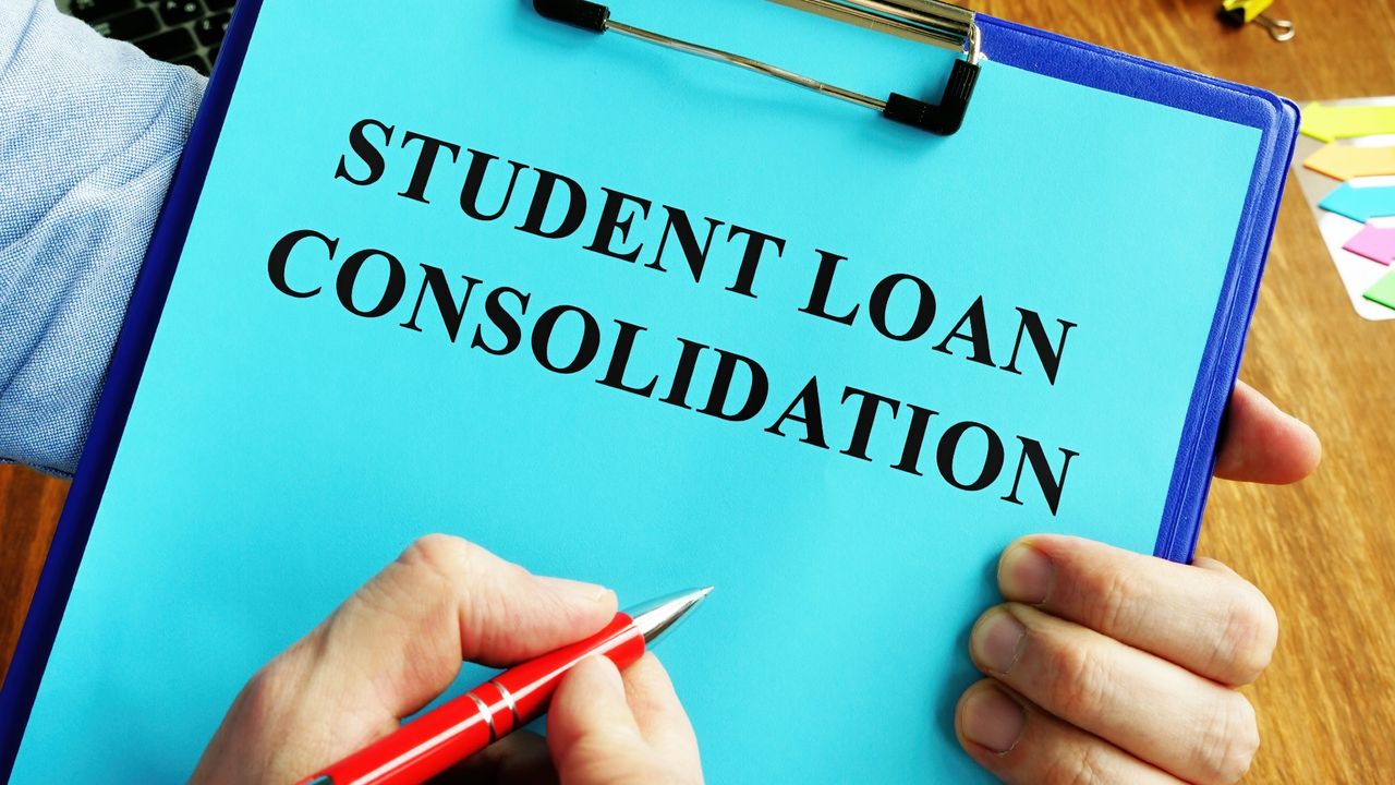 Hands holding a clipboard with a blue piece of paper on it that reads &quot;student loan consolidation&quot;