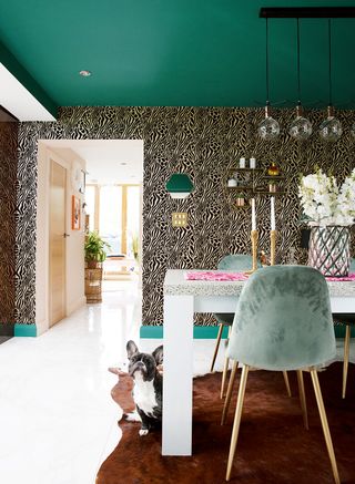 Bold and bright dining room with a turquoise painted ceiling and animal print wallpaper