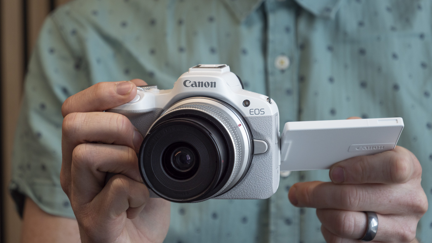 Canon EOS R50 holdes i en persons hender