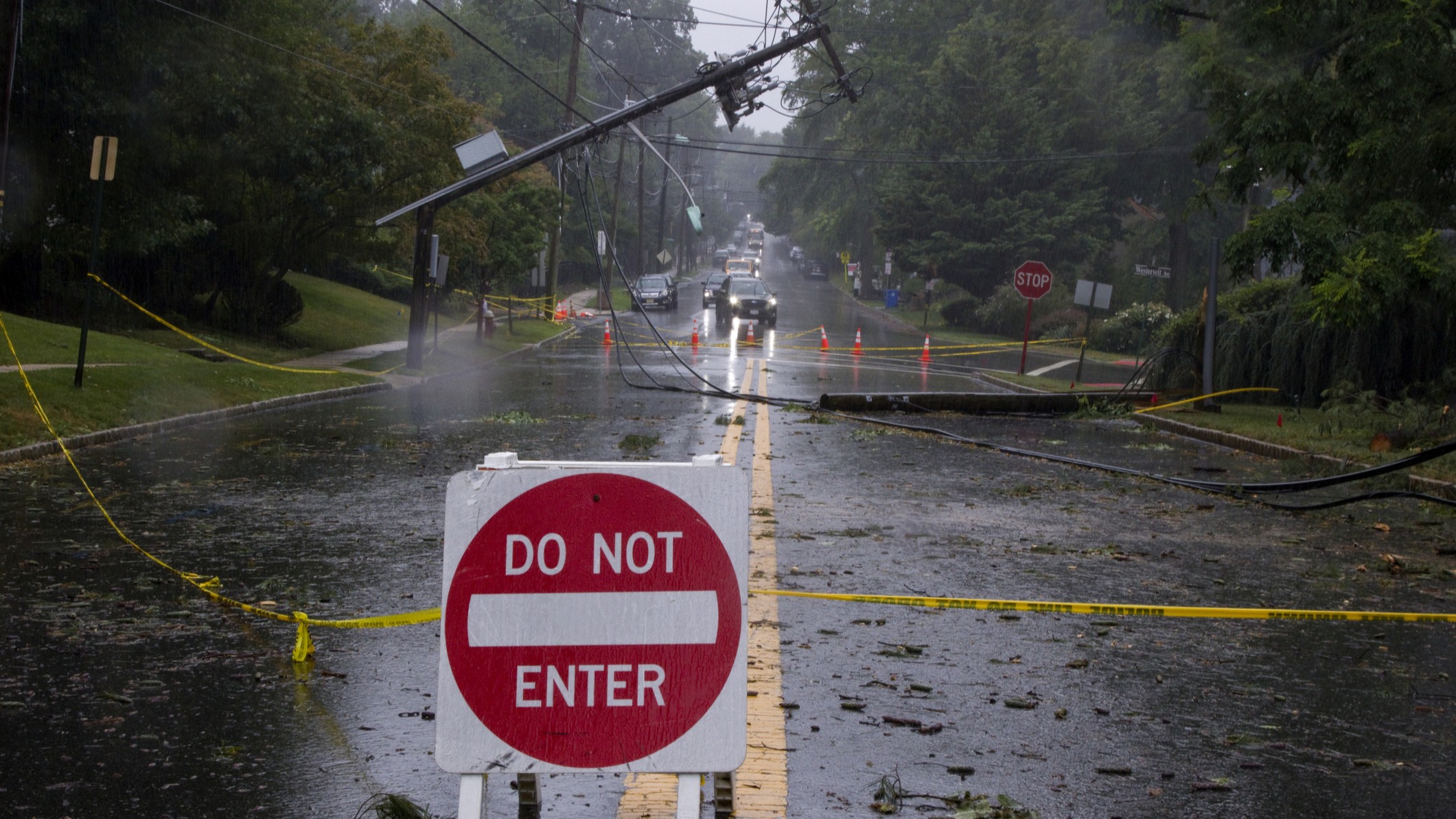 Storm damage with downed electrical pole and wires on residential street.