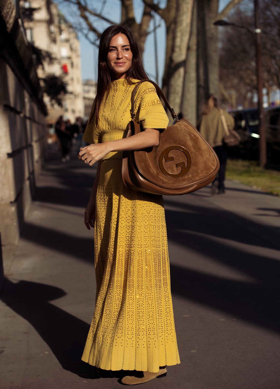 Gala Gonzalez wears brown suede Gucci bag, knitted mustard yellow skirt, matching top outside the Elie Saab fashion show during the Womenswear Fall/Winter 2025/2026 as part of Paris Fashion Week on March 08, 2025 in Paris, France