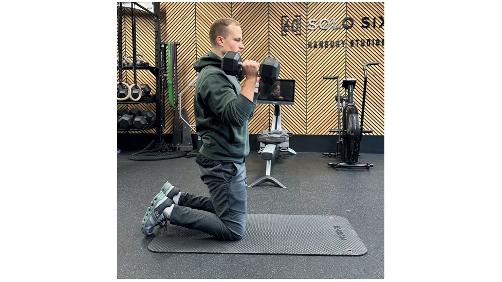 Ollie Thompson performing a tall-kneeling biceps curl and press