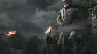 Avowed reveal trailer - Two flaming arrows soar through a foggy mountain range near a large statue of a warrior and dog carved into a mountainside.