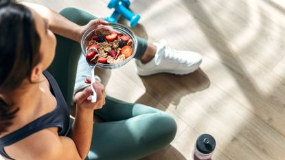 A woman eating cottage cheese, cereal and fruit at home