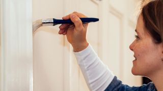 Person painting wooden wall with paintbrush