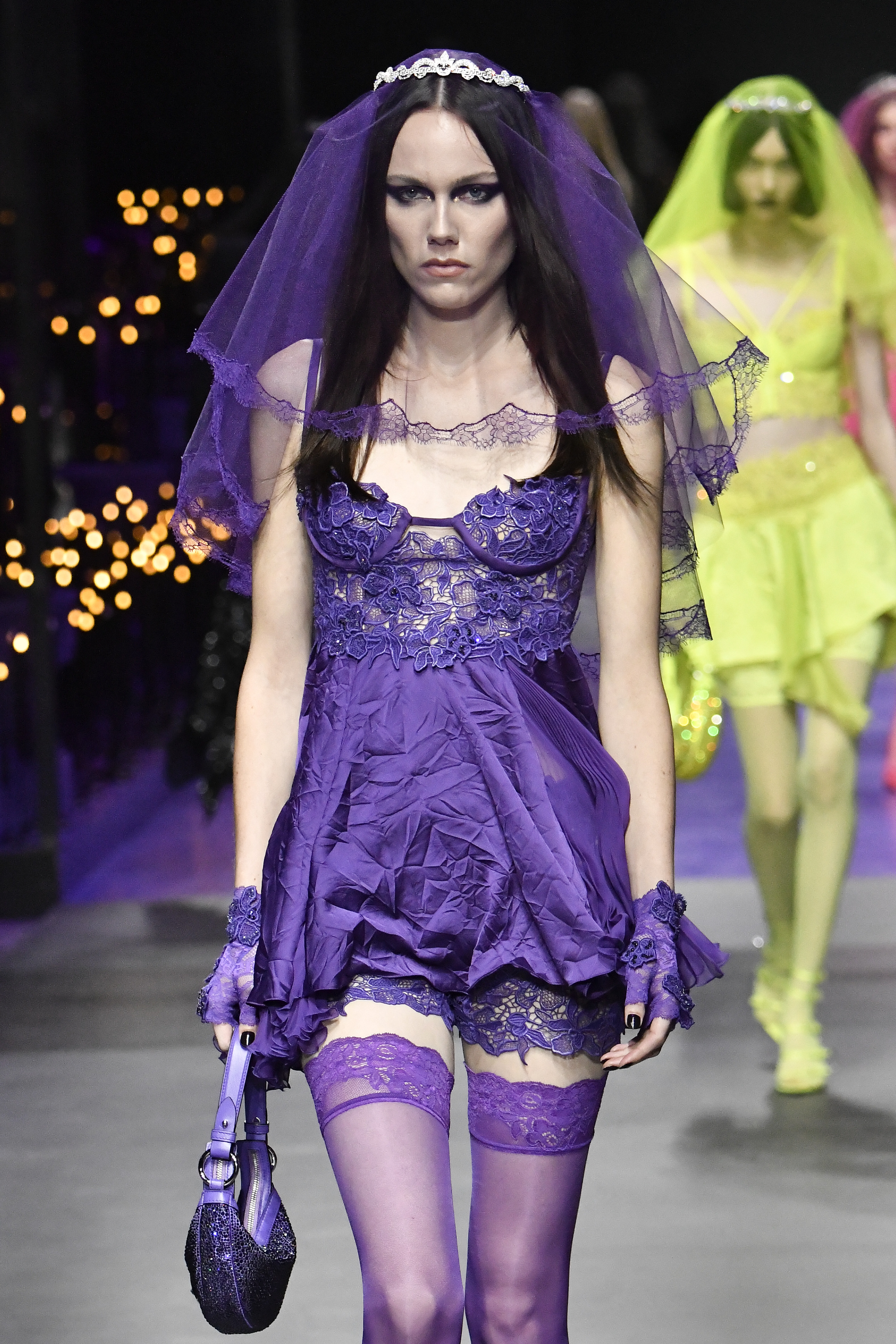 a model walks the runway wearing a wrinkled purple dress and a veil
